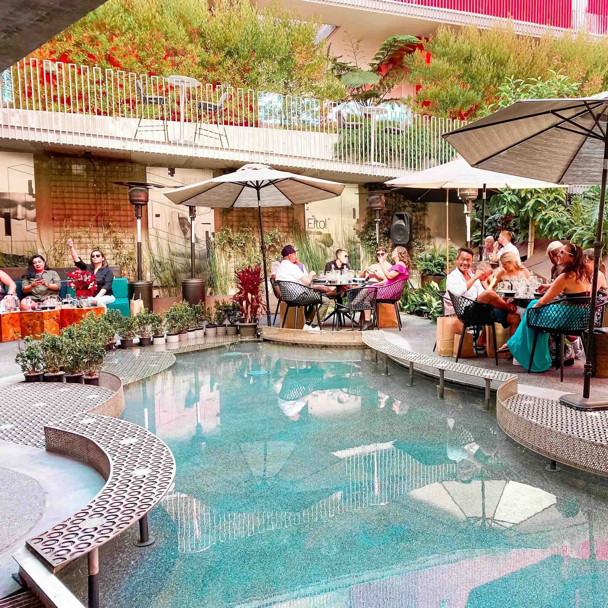 A sunny, bustling brunch patio at a popular Hillcrest restaurant on a weekend morning.